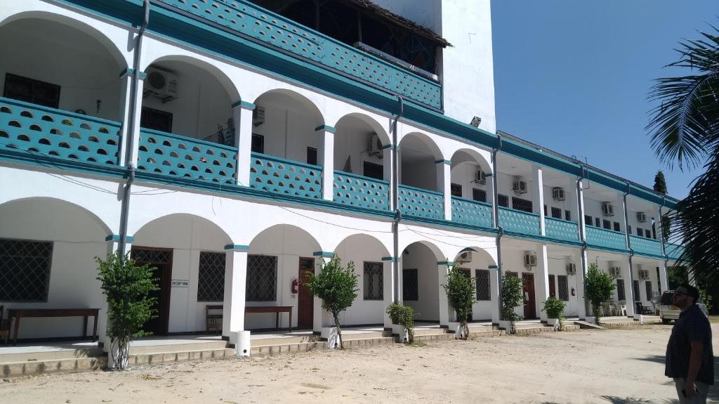 a large white building with a blue balcony at Cefa Hostel in Dar es Salaam