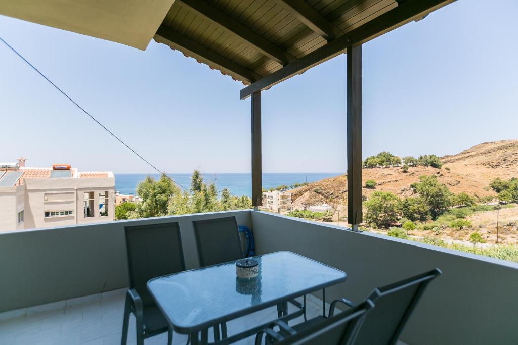 a table on a balcony with a view of the ocean at Elena's Apartment in Panormos Rethymno