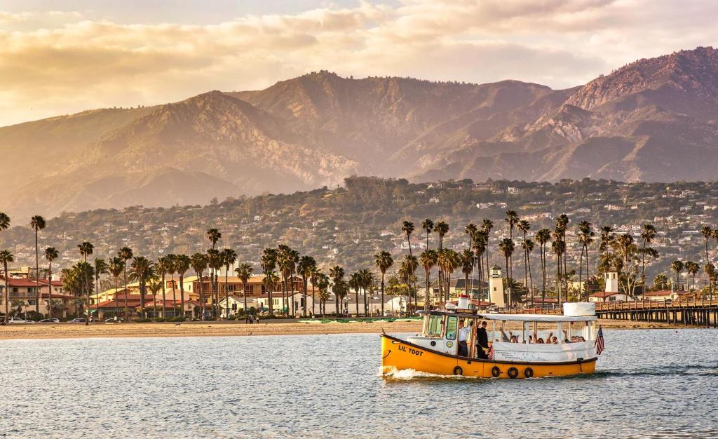 un bateau jaune dans l'eau avec des palmiers et des montagnes dans l'établissement Ocean Breeze 3 br Vacation Home, à Santa Barbara