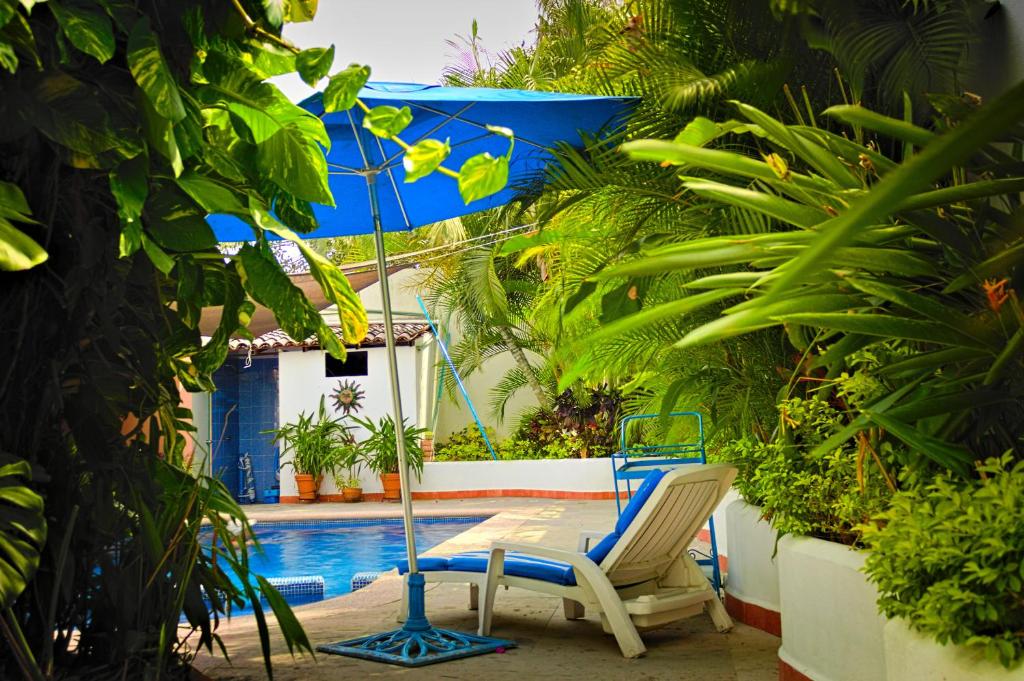um par de cadeiras e um guarda-sol ao lado de uma piscina em Casa las Flores em Puerto Vallarta