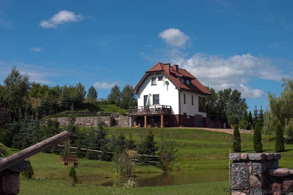 uma grande casa branca numa colina com um lago em Dom nad jeziorem Blanki em Suryty