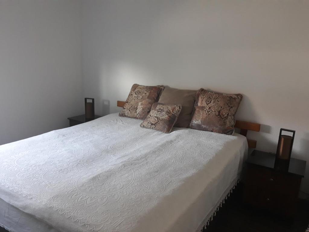 1 dormitorio con 1 cama con sábanas y almohadas blancas en Apartment AMRA, en Tuzla