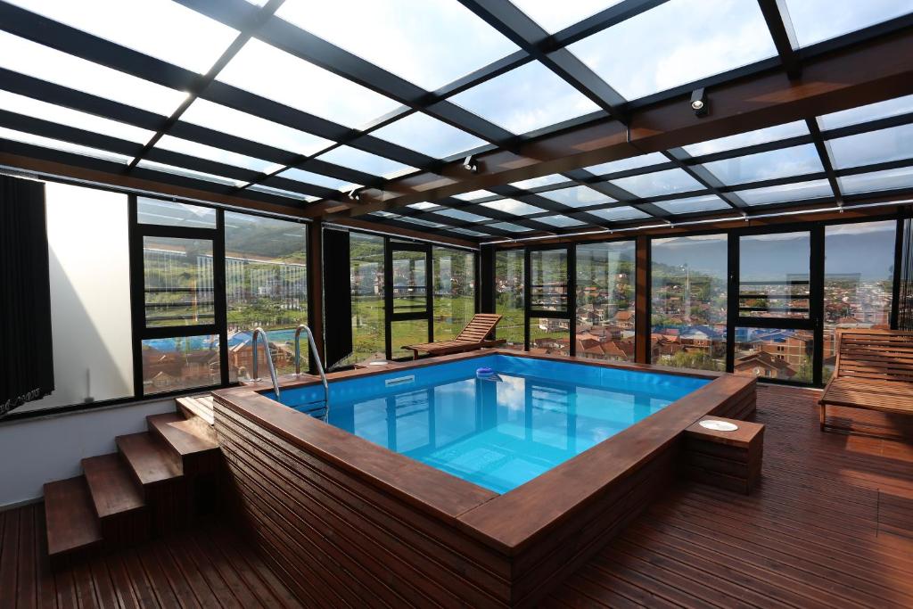 a large swimming pool in a building with windows at Kuint Hotel in Peje