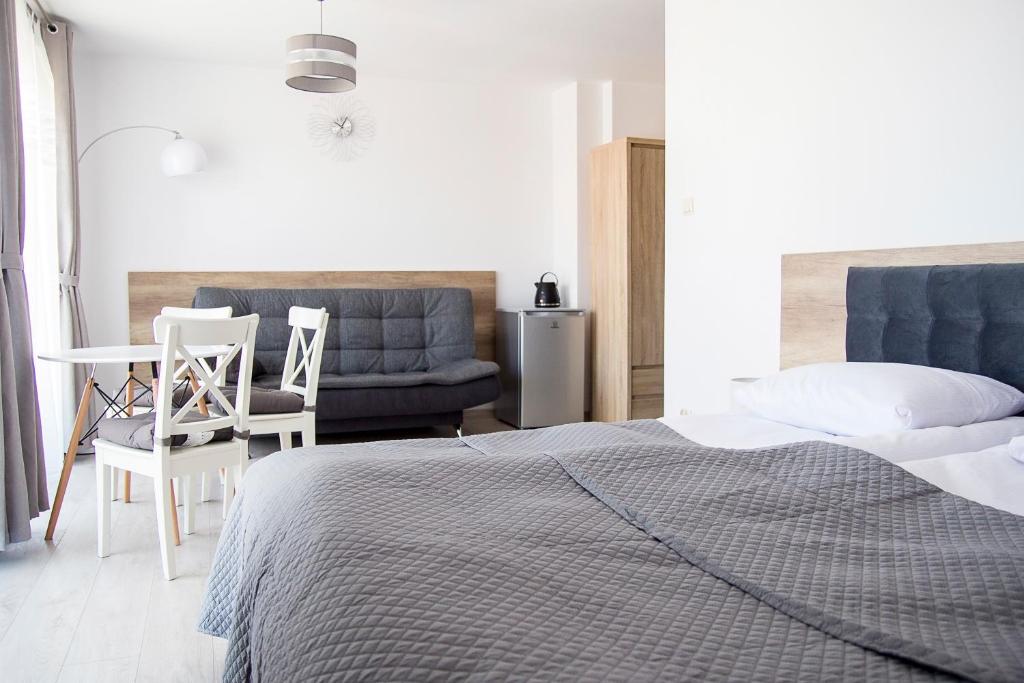 - une chambre avec un lit, une table et un canapé dans l'établissement Silver Apartments, à Sarbinowo