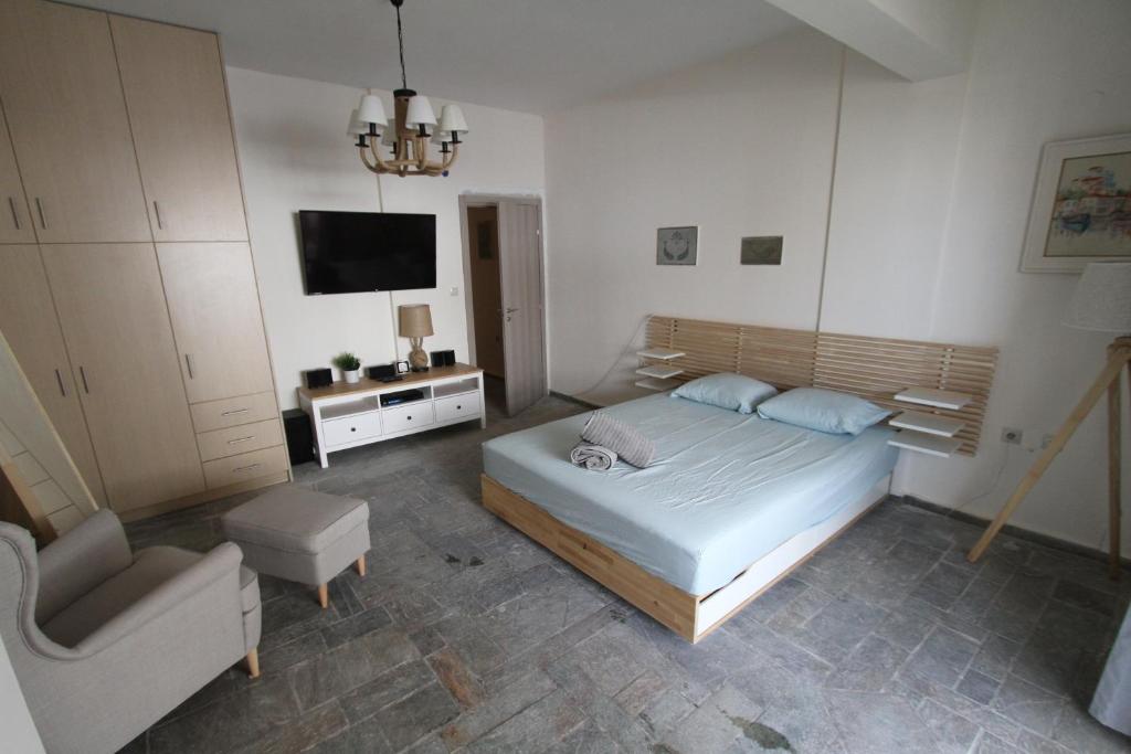ein Schlafzimmer mit einem Bett, einem Stuhl und einem TV in der Unterkunft Katerina's in Néa Palátia