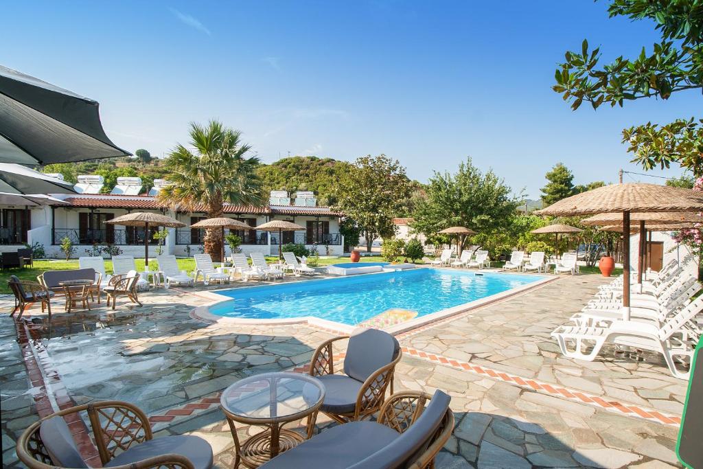 a pool with chairs and tables and umbrellas at STRAWBERRY Skiathos in Agia Paraskevi