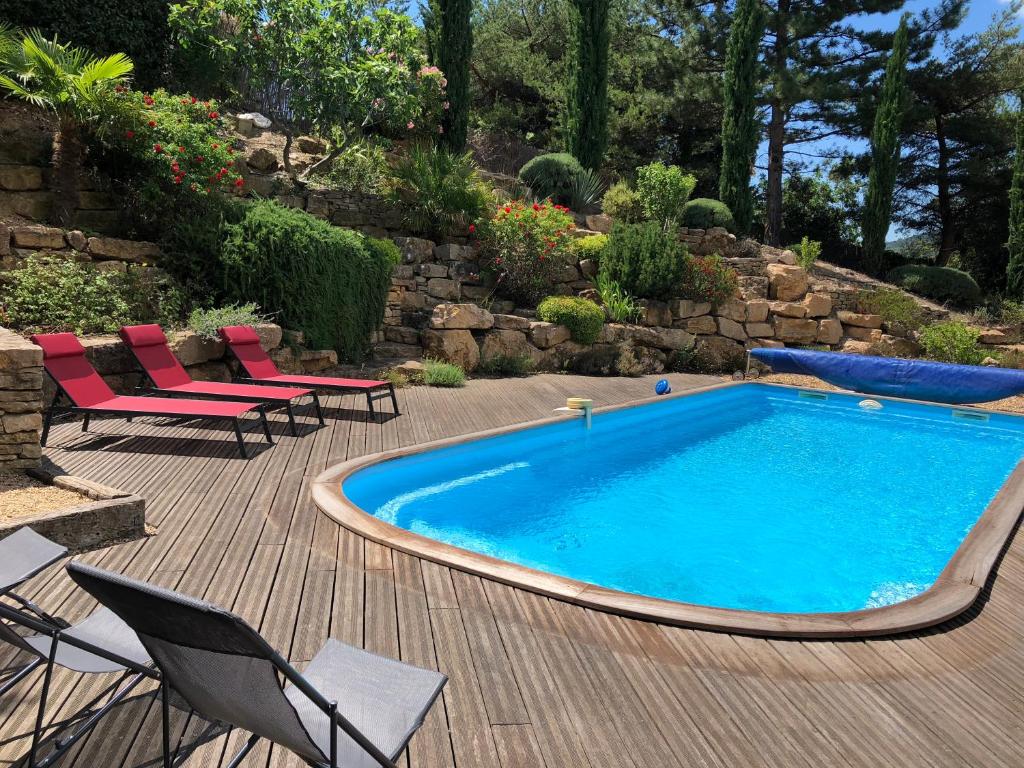 una piscina en una terraza de madera con sillas junto a en Maison avec piscine privative, en Nyons