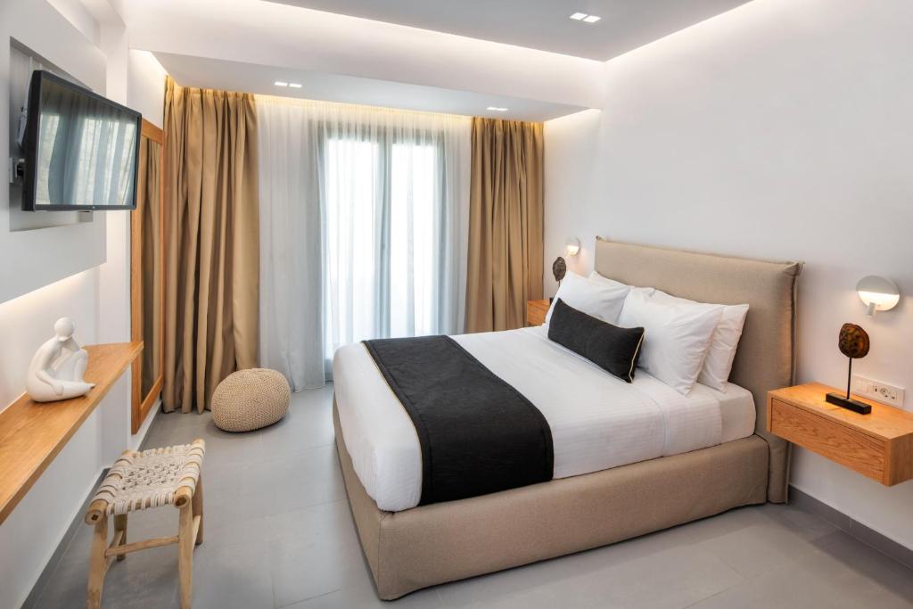 a hotel room with a bed and a television at Harmony Suites in Fira