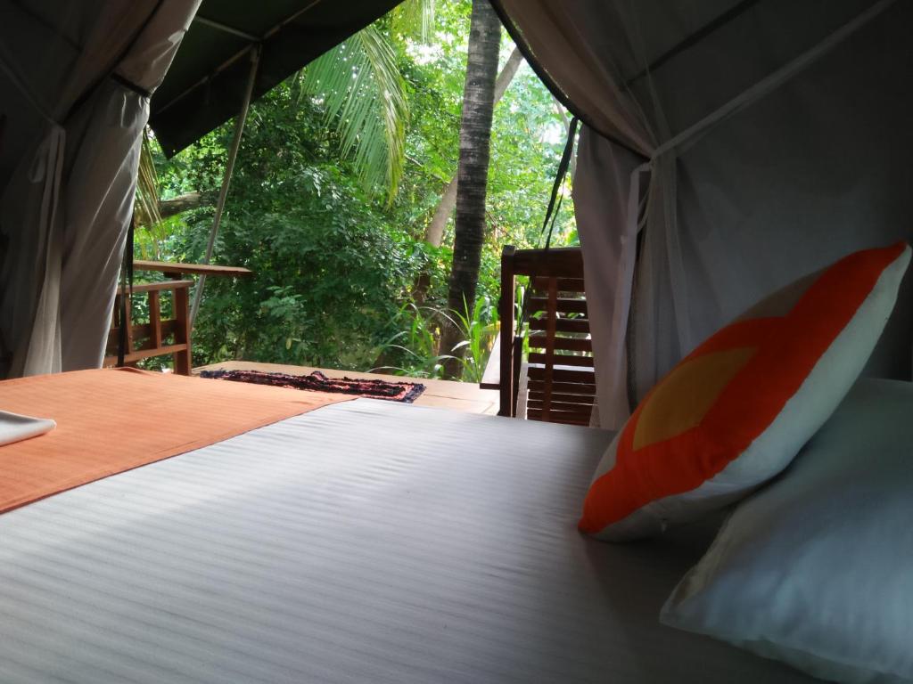 a bed in a tent with a view of the forest at Makulu Safari Camping in Udawalawe