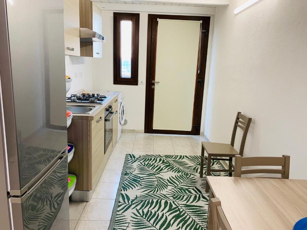 a kitchen with a refrigerator and a counter with a table at Luxar room in Assemini