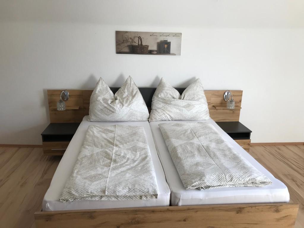 a bed with white sheets and pillows on it at Gästehaus Blümel in Köflach