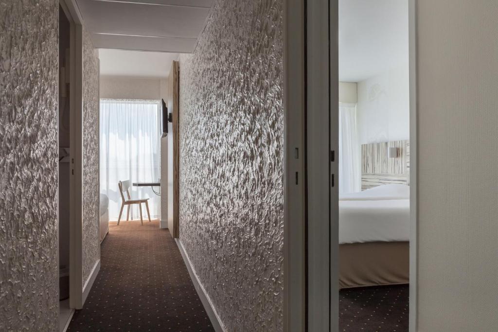 a corridor of a hotel room with a bedroom at Hôtel Le Nautic in Arcachon