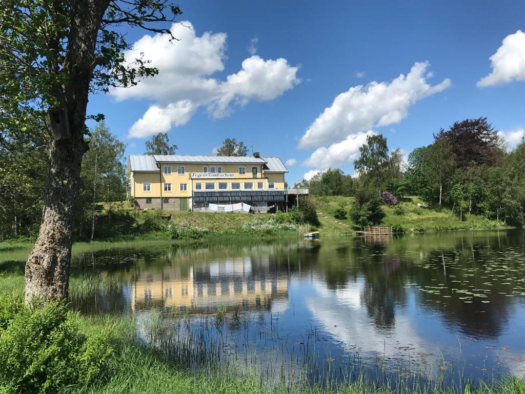 a large yellow building next to a lake at Fegens Vandrarhem in Fegen