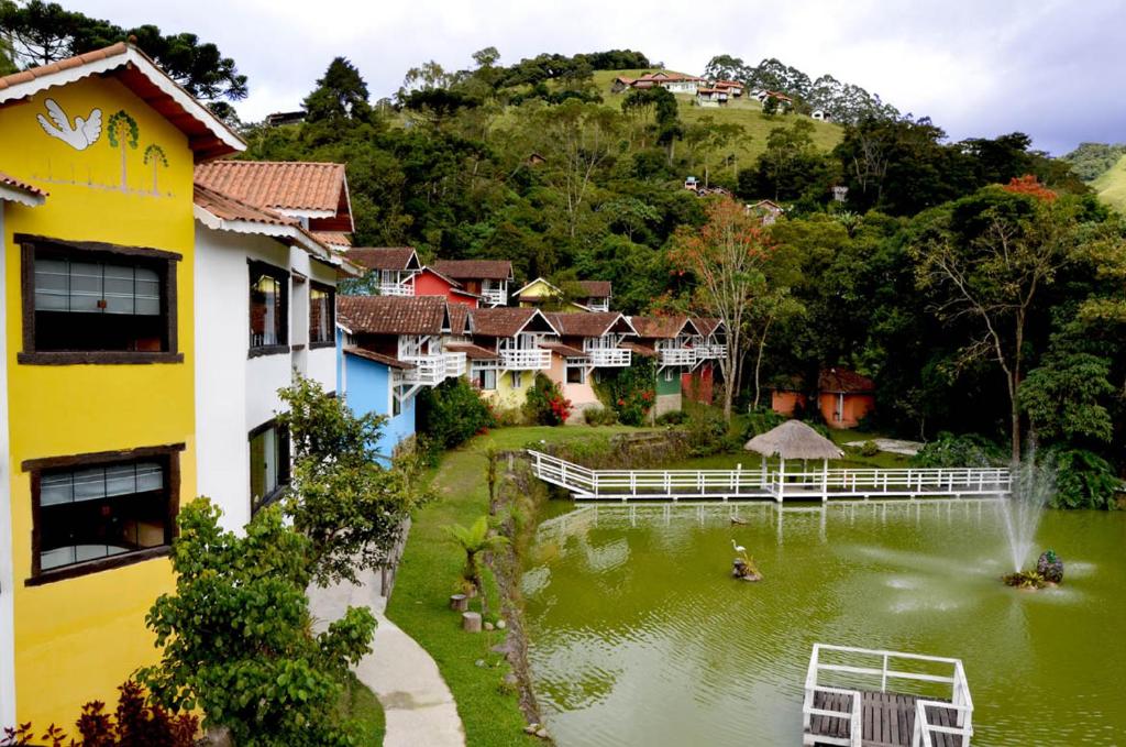 uitzicht op een dorp met een vijver en huizen bij Pousada Chalés do Lago in Visconde De Maua