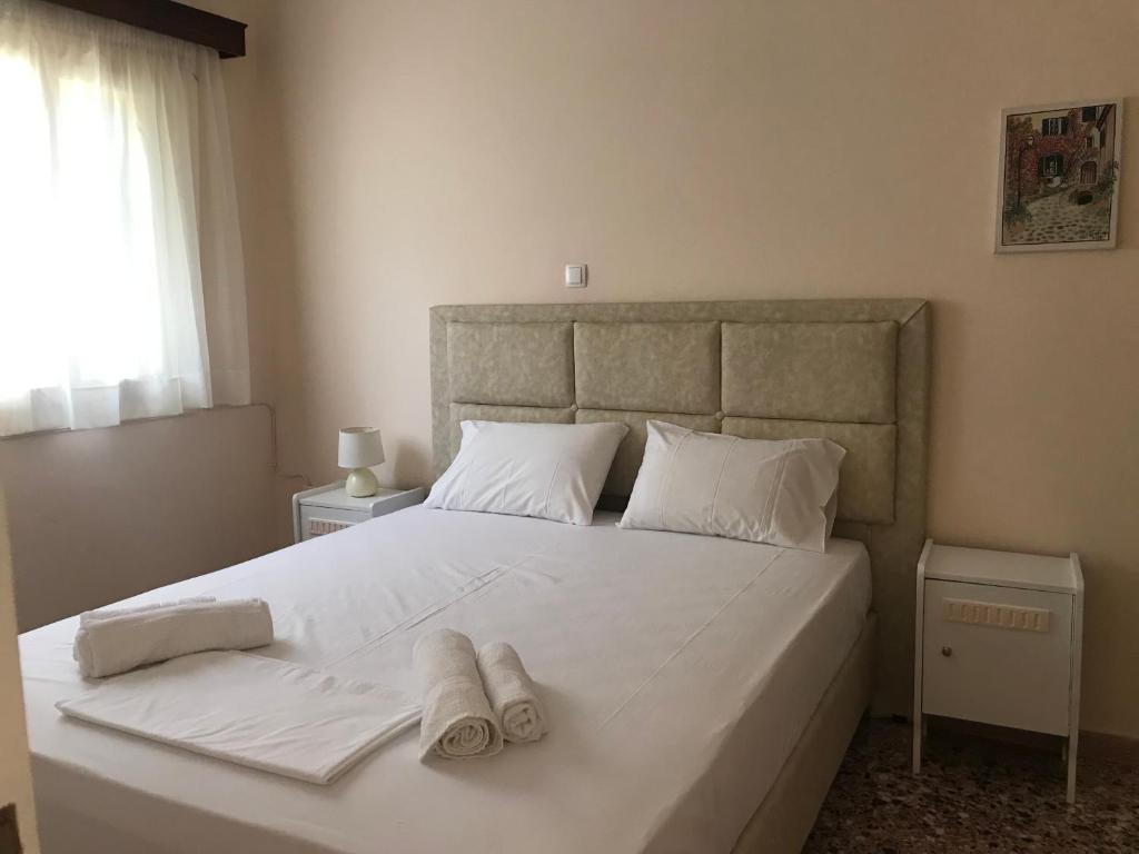 um quarto com uma cama branca e toalhas em Natalia Studios em Poros
