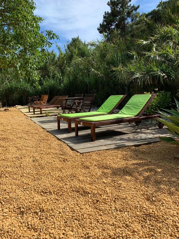 a row of lounge chairs with green cushions on a patio at Quinta do Meco - Beach & Nature in Aldeia do Meco