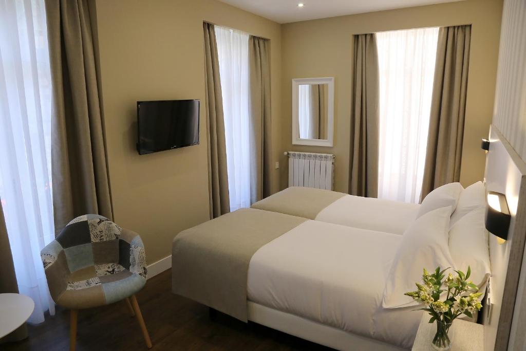 Habitación de hotel con cama blanca y silla en VÍA XIX, en Caldas de Reis