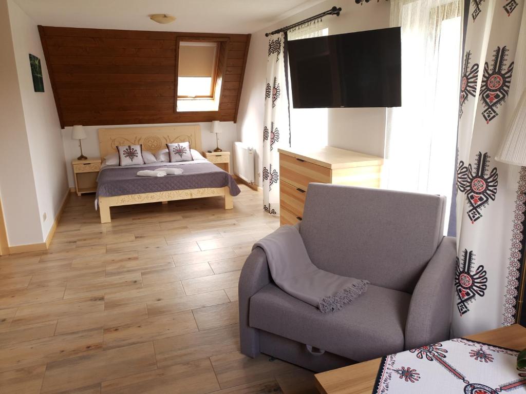 a bedroom with a bed and a chair and a television at u Sabiny in Białka Tatrzańska
