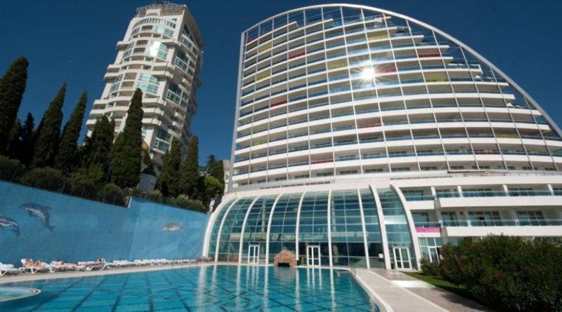 a large building with a pool in front of it at Ялта Respect Hall in Yalta