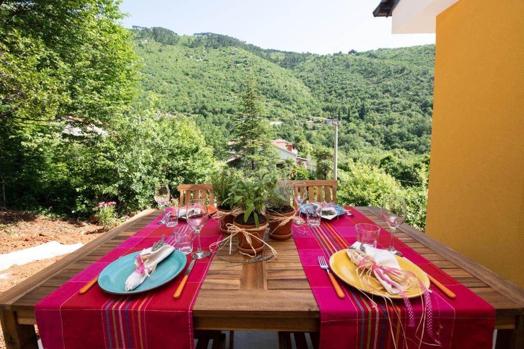 a wooden table with a red tablecloth on a table with a view at Apartman Villa Katrina in Mošćenička Draga