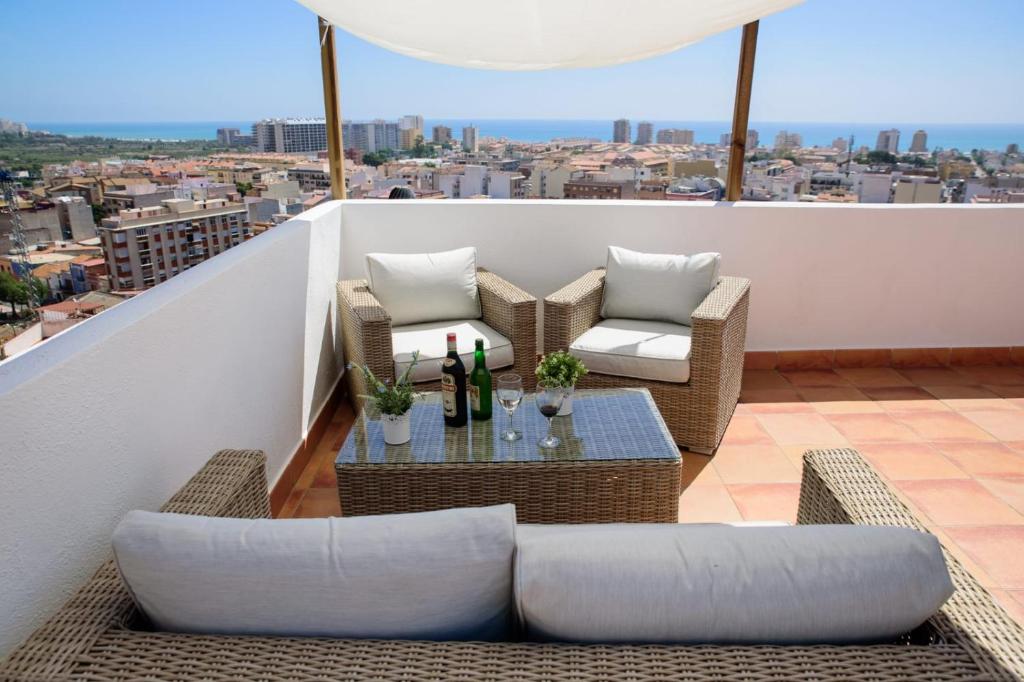 奧羅佩薩德爾馬的住宿－L'Atalaya D'or，阳台配有藤椅和带葡萄酒瓶的桌子。