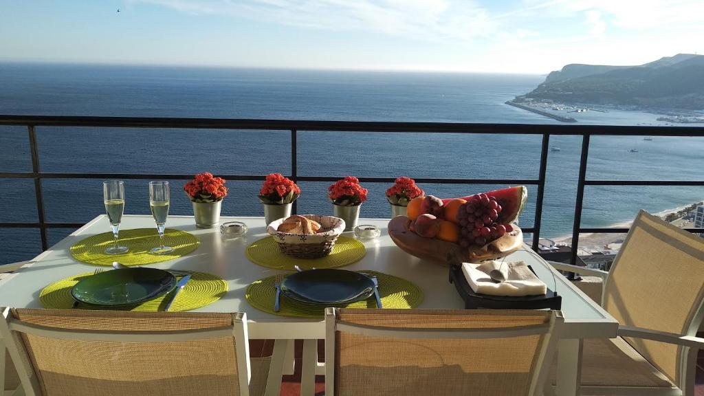 einen Tisch mit Speisen und Meerblick in der Unterkunft Edifício Panorâmico - Falésia de Sesimbra in Sesimbra