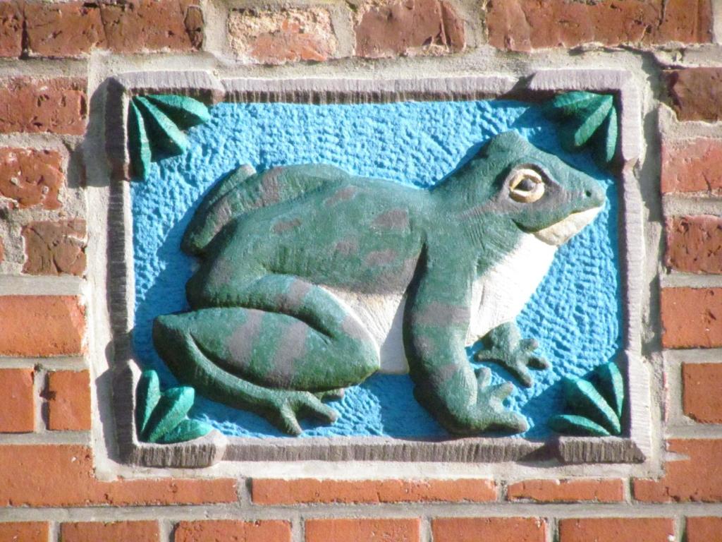 un lagarto verde en una pared de ladrillo en Apartments im Froschhaus mit Frühstücksküchen en Friedrichstadt