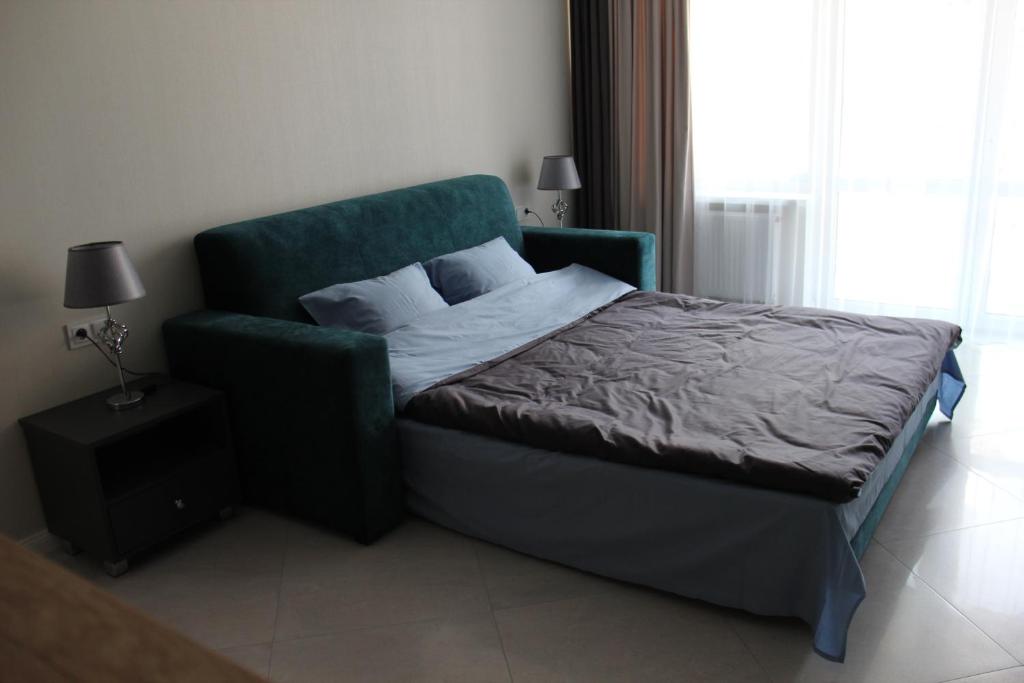 a bedroom with a bed and a green chair at Apartment on Bratskaya 6 in Minsk