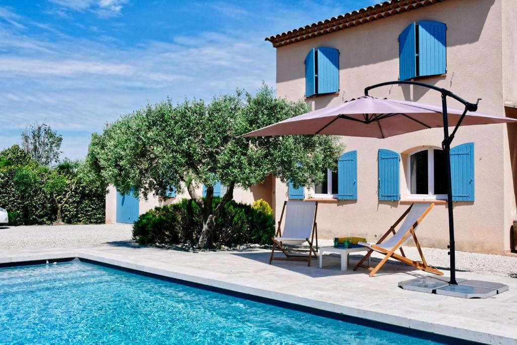 a villa with a swimming pool and an umbrella and chairs at Villa Louanne in Pertuis