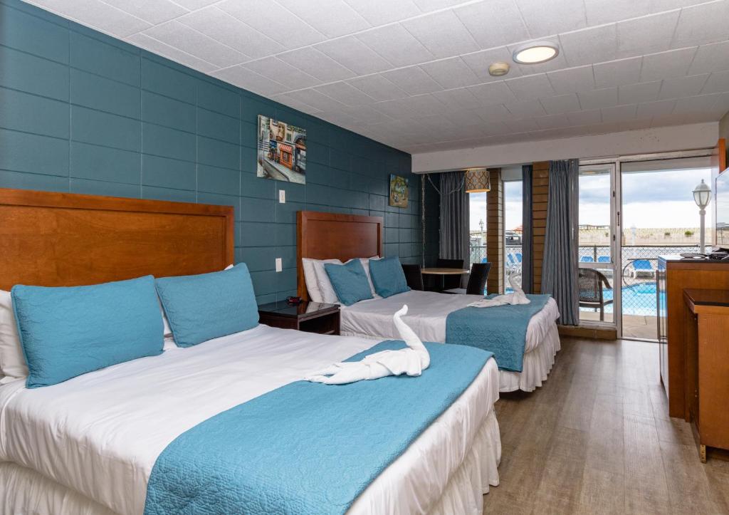 Habitación de hotel con 2 camas y paredes azules en Charlroy Motel, en Seaside Park