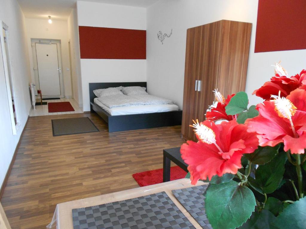 Zimmer mit einem Bett und einer Vase mit roten Blumen in der Unterkunft Apartment Beethoven in Regensburg