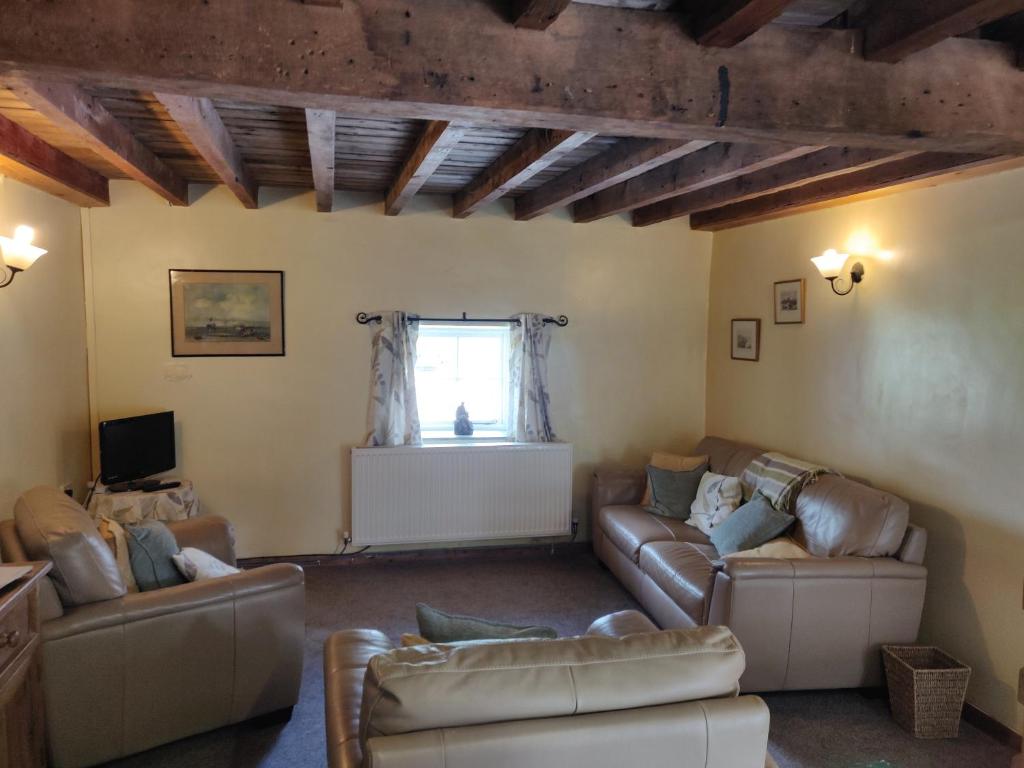 a living room with two couches and a window at Row Farm Cottage in Millom