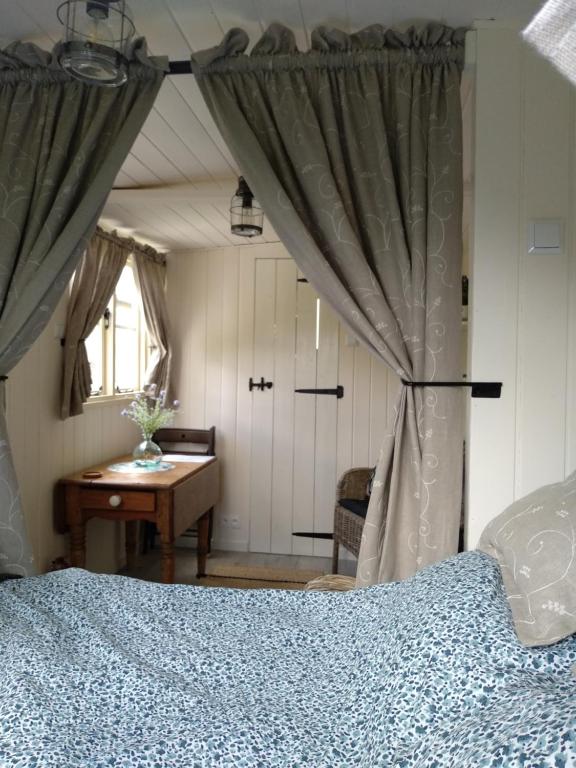 1 dormitorio con cama, mesa y ventana en The English shepherds hut @ Les Aulnaies, en Échauffour