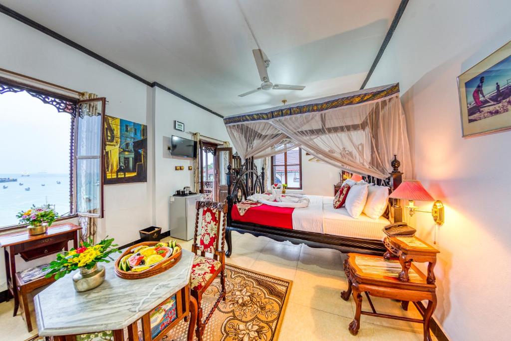 a bedroom with a large bed and a table and chairs at Tembo House Hotel in Zanzibar City