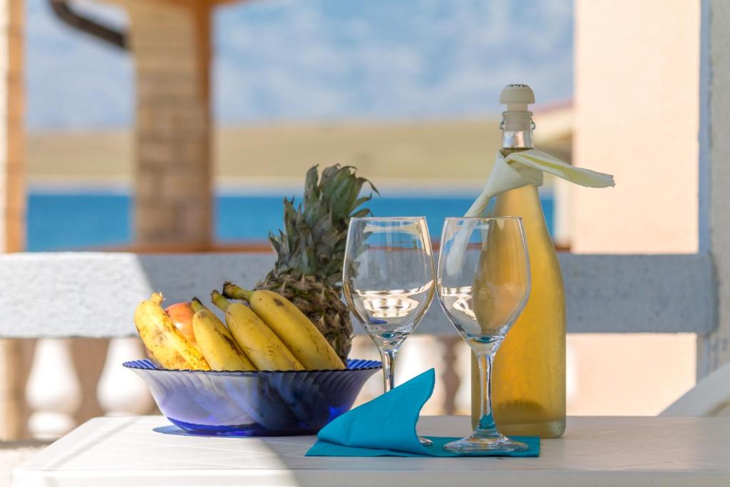 - un bol de bananes et deux verres à vin sur une table dans l'établissement Fisa Apartments, à Vir
