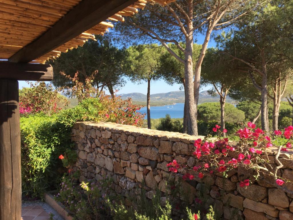 a stone wall with flowers and a view of the water at Conca Verde in Conca Verde