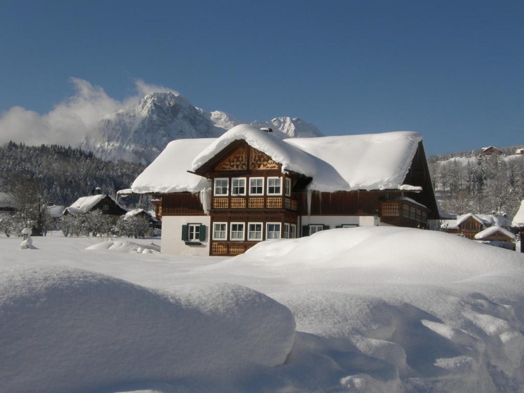 ein schneebedecktes Haus mit Bergen im Hintergrund in der Unterkunft Haus Sonja in Altaussee