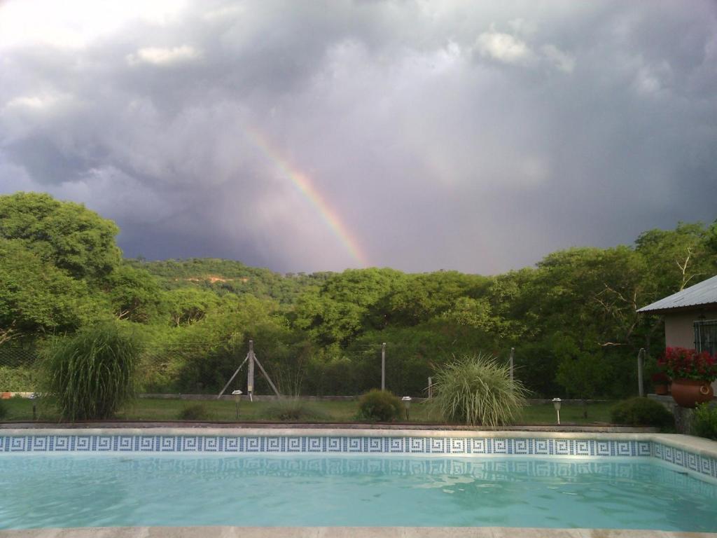薩爾塔的住宿－Cabaña la linda Vaqueros，一座带房子的游泳池上的彩虹