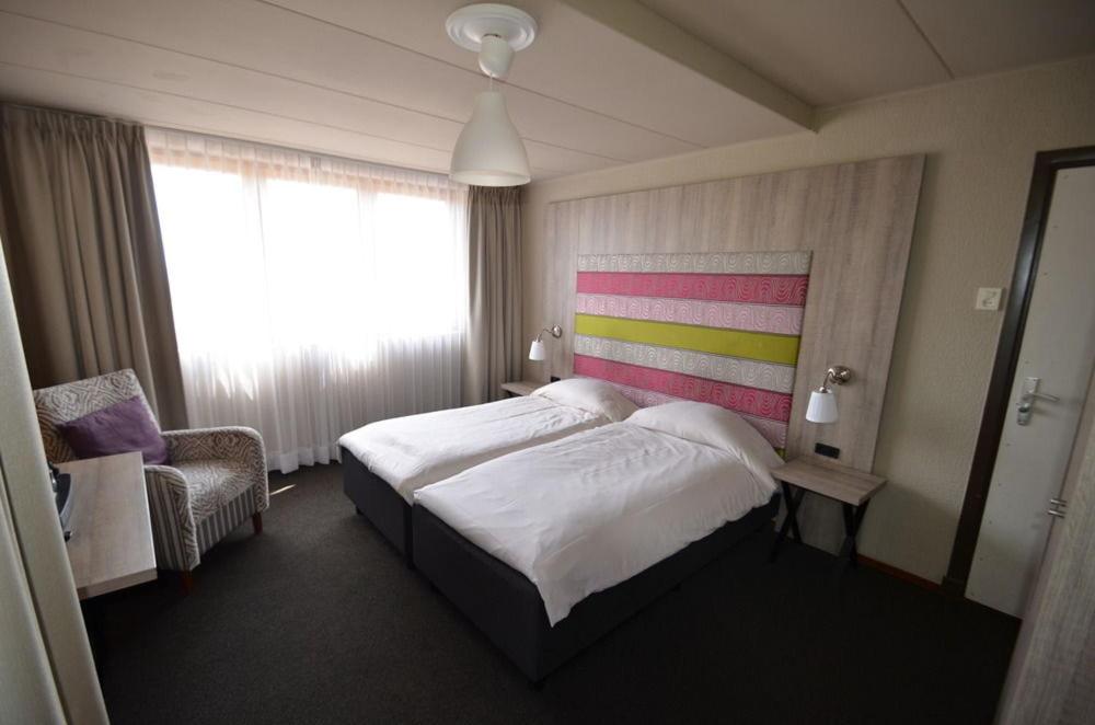 een hotelkamer met een bed en een stoel bij Herberg 't Voshoes in Mechelen