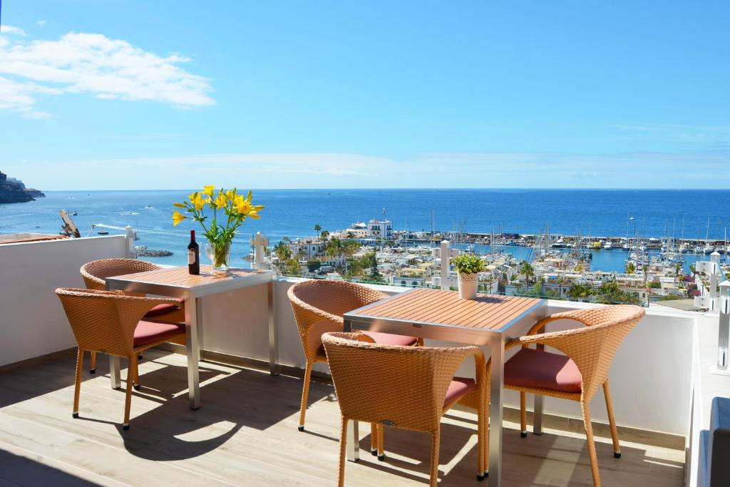 a balcony with tables and chairs and a view of the ocean at Bella Vista Sun Club in Puerto de Mogán