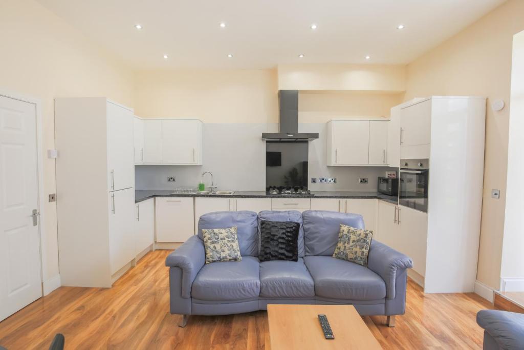 a living room with a blue couch and a kitchen at Stylish Modern 4 Bed Apartment in Edinburgh