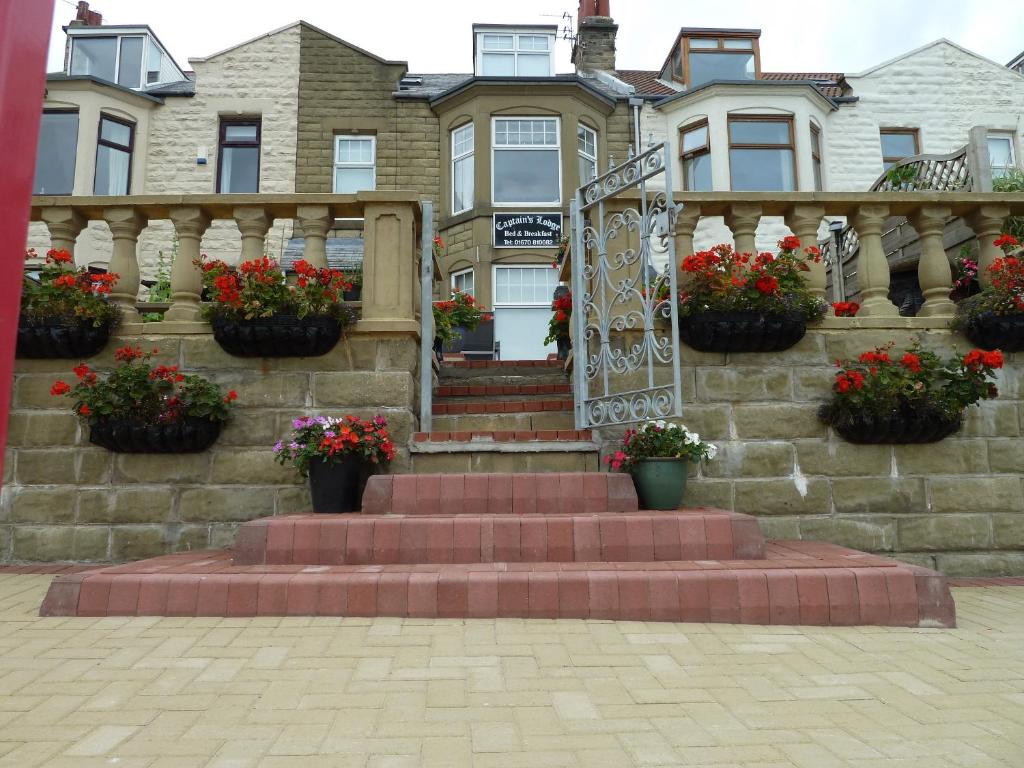 a house with potted flowers on the stairs at Captains Lodge in Newbiggin-by-the-Sea