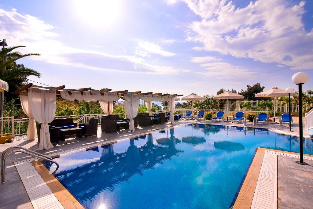 a large swimming pool with chairs and umbrellas at Hotel Diamond in Limenaria