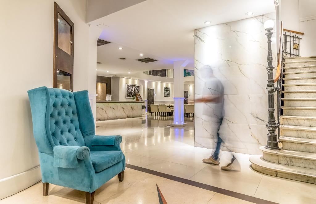 a man walking through a lobby with a blue chair at Up Tribeca in Buenos Aires