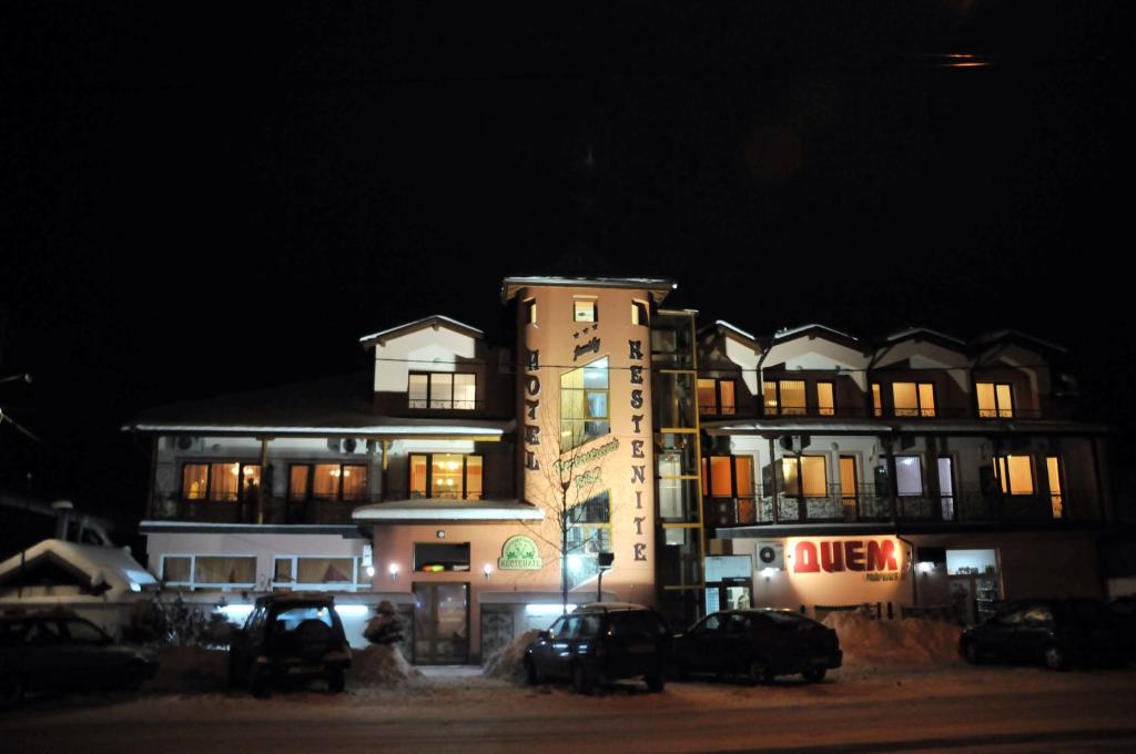 un edificio con coches aparcados delante de él por la noche en Kestenite Family Hotel, en Samokov