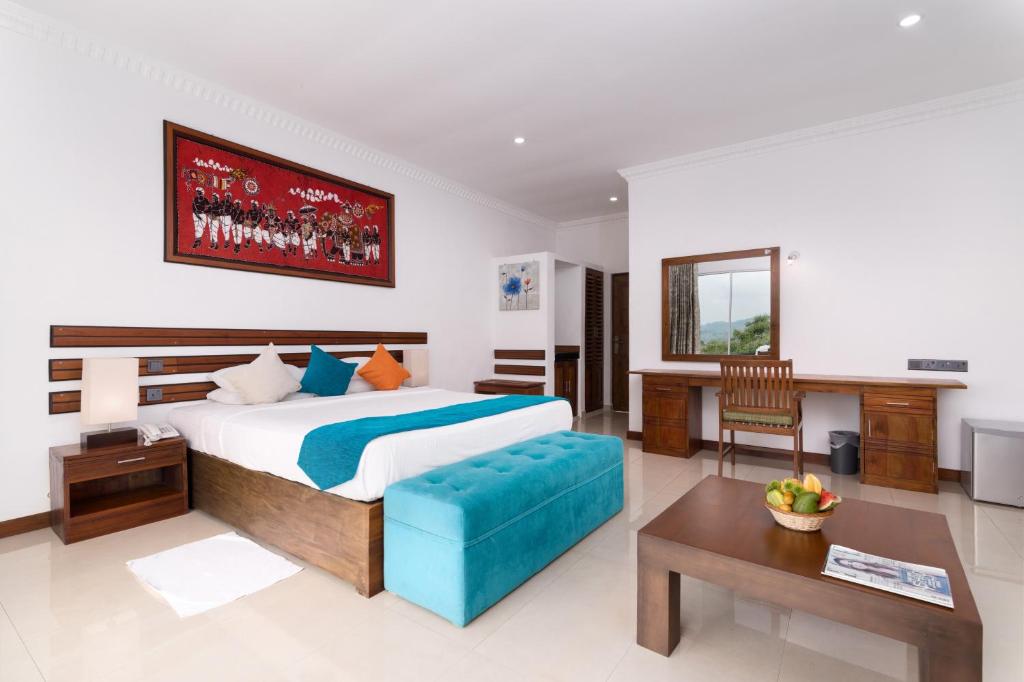 a bedroom with a large bed and a desk at Elegant Hotel in Kandy