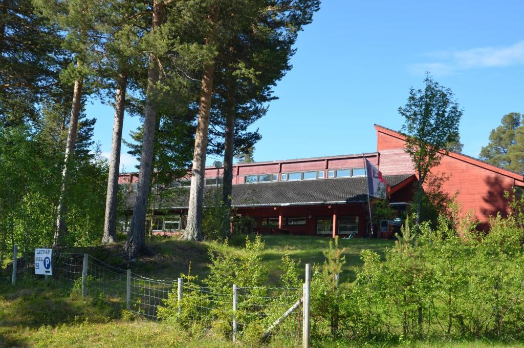 a red building with a fence and trees at Gjesteheim Havdal in Sundset