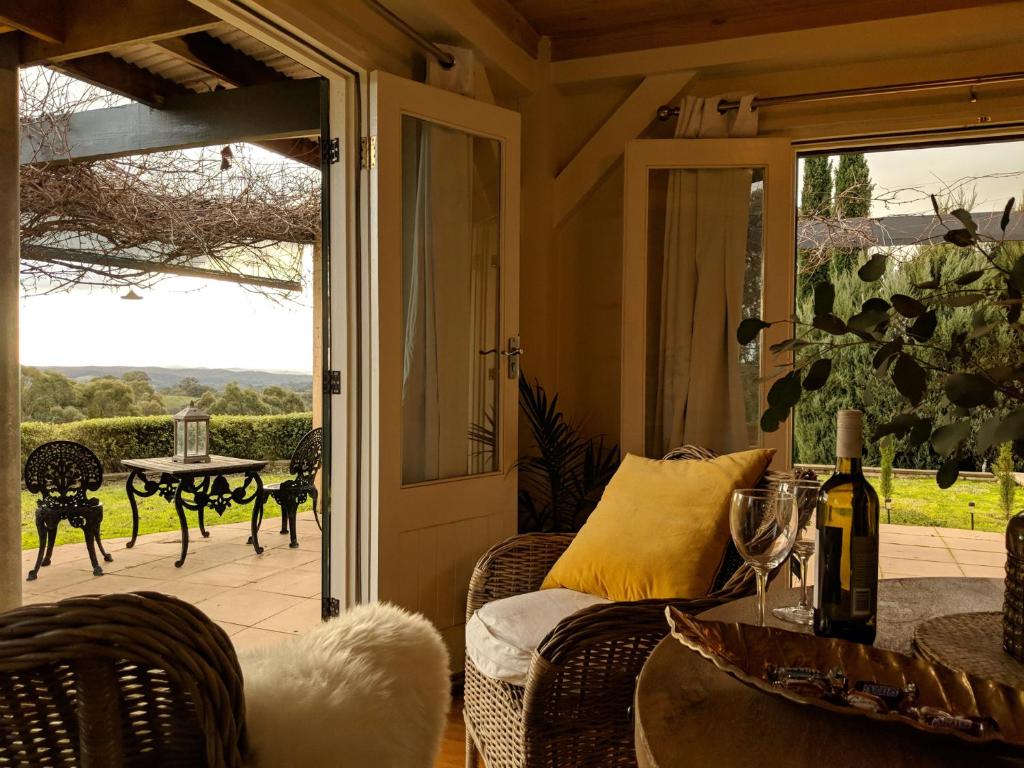 a porch with a couch and a table and a glass door at El Camino country cottage with terrace and stunning views in Hepburn Springs