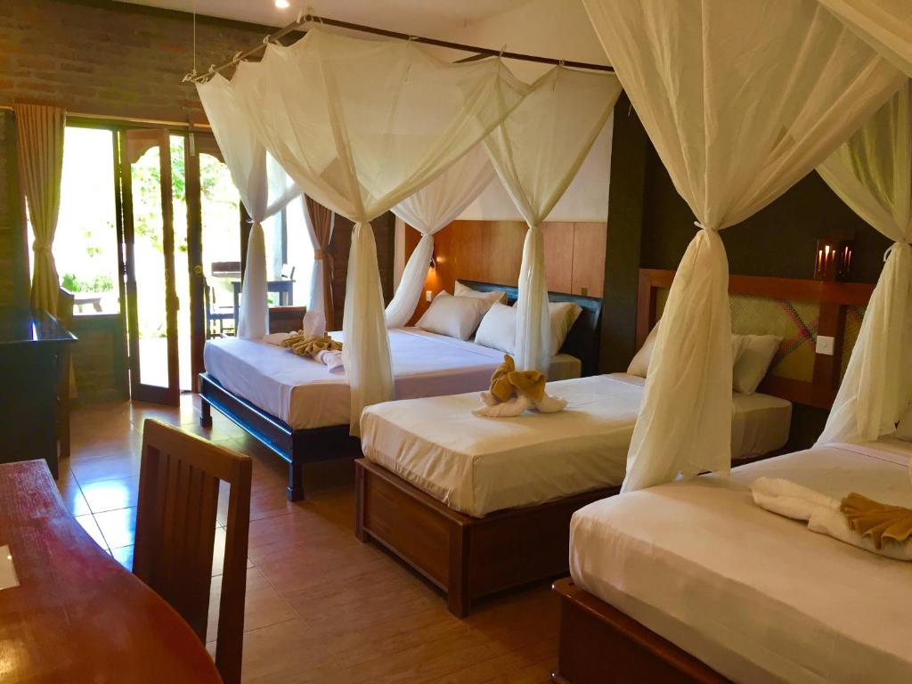 a bedroom with two beds with mosquito nets at Villa Dika Pemuteran in Pemuteran