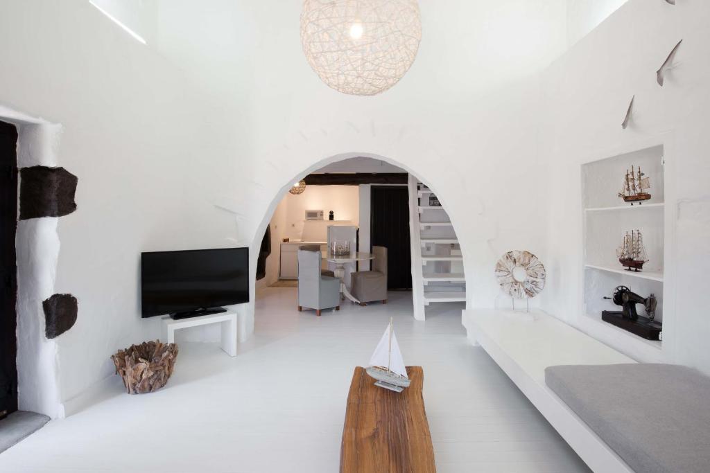 a white living room with a tv and a couch at Monastery Estate Guesthouse in Sougia
